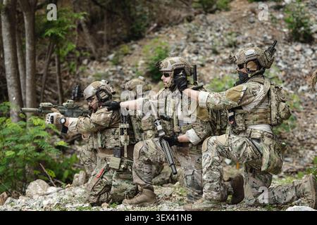 Military communications soldier operating tactical radio equipment during field mission, Advanced Battlefield Communication Systems, Special Forces Si Stock Photo