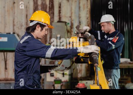 Professional engineer workers team working in metal workshop working together check service robot arm welder machine Stock Photo