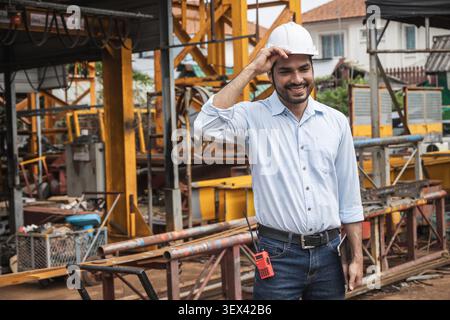 Portrait Happy Smiling Asian Indian construction Engineer male, Builder lead construction site working control operate crane site. Stock Photo