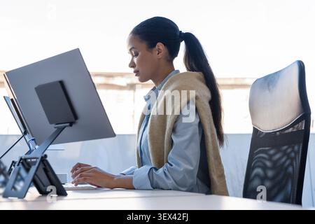 Focused young woman typing on keyboard in office Stock Photo