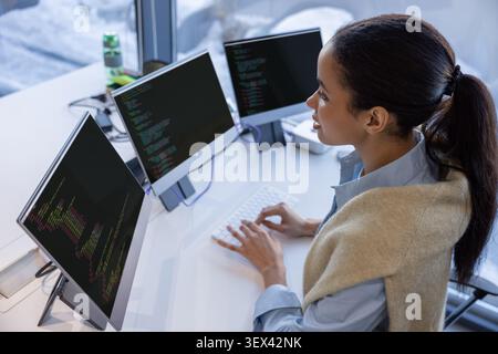 Woman engineer programming on multiple screens in office Stock Photo