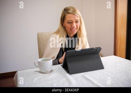 Woman smiling, engaged in a conversation or work from home using a digital tablet Stock Photo