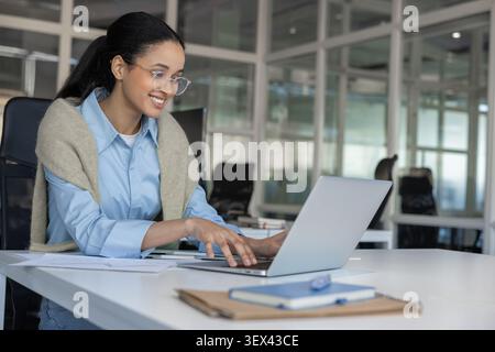 Happy female employee working on laptop Stock Photo