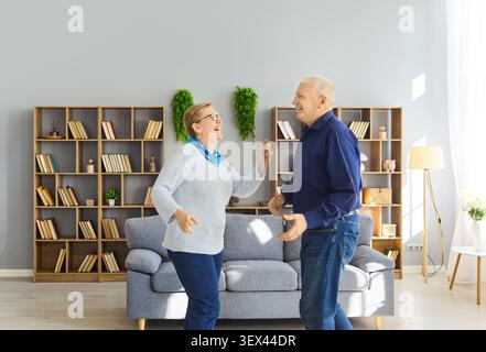 Smiling senior couple dancing at home, celebrating love, wellness and vitality Stock Photo