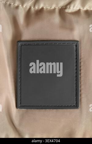 Blank black rubber patch stitched on beige waterproof fabric background Stock Photo