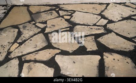 Broken stone pavement with dark mortar and weathered texture Stock Photo