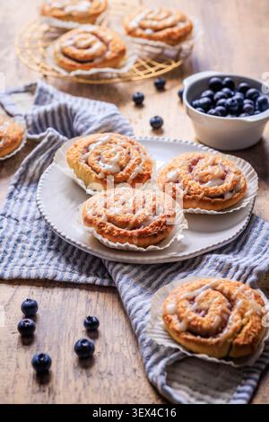 Delicious blueberry cinnamon rolls with sweet icing on a rustic wooden table Stock Photo
