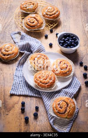 Delicious blueberry cinnamon rolls with sweet icing on a rustic wooden table Stock Photo