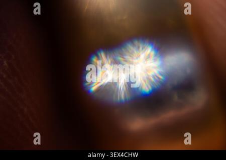 Abstract light flare bursting through darkness with prismatic diffraction streaks radiating outward Stock Photo