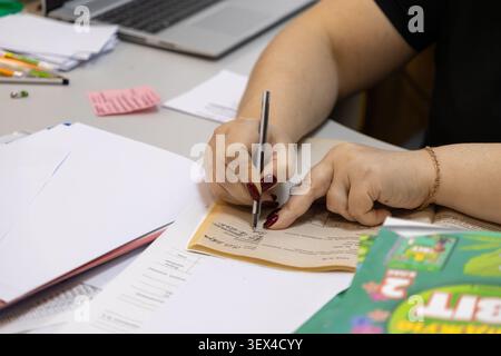 Close view of hands jotting down notes in a journal at an office desk, illustrating productivity, educational study, or daily organizational routines Stock Photo