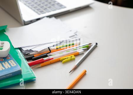 Essential workspace tools like notebooks, colorful pens, and pencils arranged on a clean desktop near a computer, representing an organized environmen Stock Photo