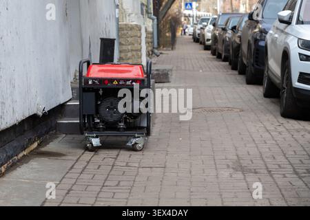 This compact gas powered generator placed on a town street highlights a reliable mobile energy supply for homes and shops facing urgent power failure Stock Photo