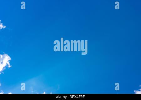 Clear blue sky with small white clouds on edges providing huge copy space. Concept: minimalist sky banner Stock Photo