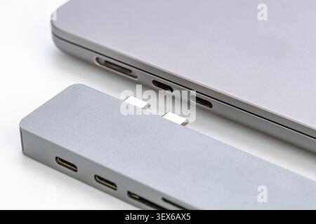 Close-up macro shot of a sleek aluminum USB-C hub adapter with dual Type-C connectors positioned next to a modern silver laptop showcasing Thunderbolt Stock Photo