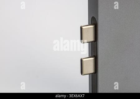 Macro close-up of two USB Type-C connectors inserted into ports of a sleek gray aluminum electronic device, showcasing the modern reversible universal Stock Photo
