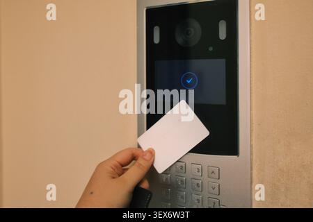 Close-up of a hand using an RFID access card on an electronic door reader with access successfully granted. Ideal for concepts of building security Stock Photo