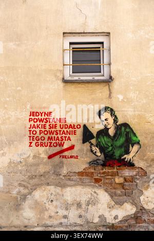 Stencil mural of woman mason troweling mortar on weathered exterior wall in Warsaw Poland Stock Photo