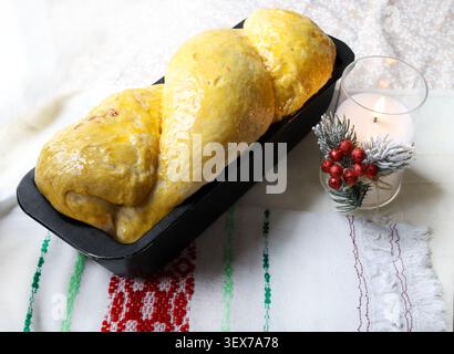 Traditional Romanian sweet bread cozonac baking in a loaf pan on Christmas holiday table setting. Christmas and holiday concept. Stock Photo