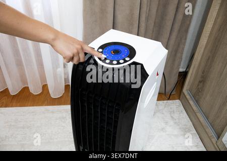 A macro horizontal view focusing on a person's index finger pressing a button icon on the glowing blue circular digital touch screen interface control Stock Photo