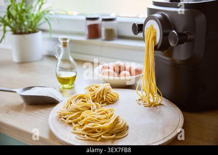Fresh homemade pasta being made with pasta machine in bright kitchen Stock Photo