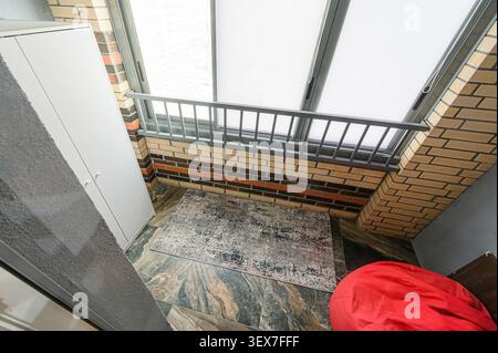 High-angle shot of an interior space featuring a red beanbag, brick wall, rug, and skylights, creating a cozy and modern look Stock Photo