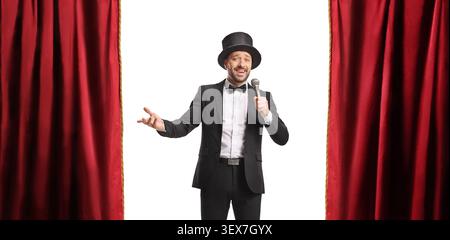 Man in a tuxedo and top hat holding a microphone and performing isolated on white background Stock Photo