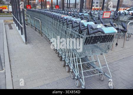 Rows of shopping carts at the entrance of a supermarket before opening hours, illustrating retail and grocery shopping - Chisinau, Moldova - March 30 Stock Photo