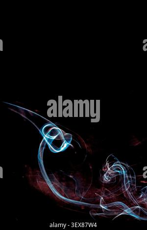 Abstract smoke trails on a black-brown dark background, blue and red wisps, flowing curved lines, copy space Stock Photo