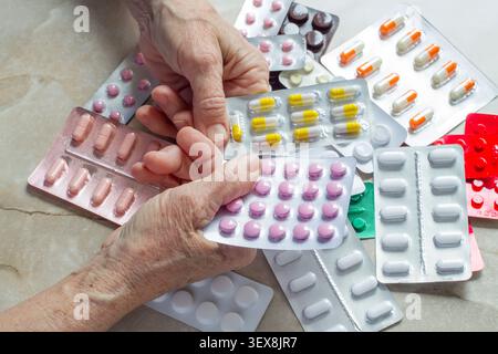 A lot of different pills. An elderly womans hands hold pills in a blister pack. A bunch of different medications. Stock Photo