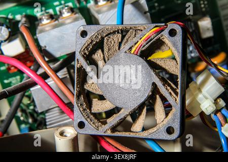 Dusty computer cooling system fan close-up. Maintenance and repair of electronics. Stock Photo