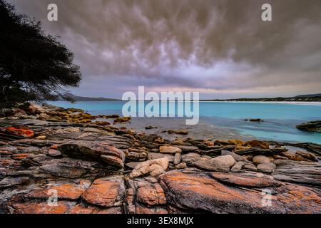 View of East Bay Camping Ground with rocky coastline, turquoise water, and dramatic stormy clouds in Manypeaks, Western Australia, Australia. Stock Photo