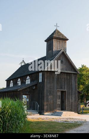 Beautiful historic wooden church with a prominent steeple, set against a clear blue sky, featuring traditional timber construction and a shingle roof. Stock Photo