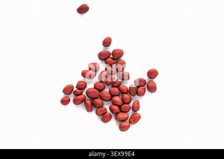 Treated daikon seeds scattered on a clean white background. Group of red coated Japanese radish seeds isolated on white Stock Photo