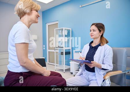 Young woman taking notes with senior female mentor in medical office Stock Photo