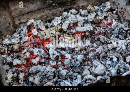 Close-up of glowing charcoal embers in a barbecue grill, producing steady heat and ready for grilling meat outdoors at a summer barbecue event. Stock Photo