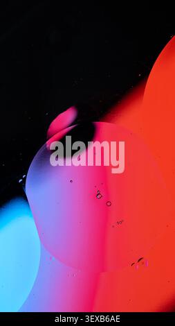 Oil drops creating an abstract pattern with gradients of red, blue, and purple color Stock Photo