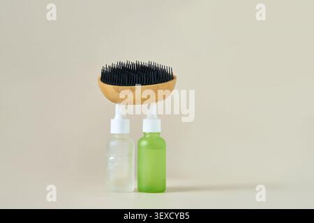 Serum Bottles Supporting Wooden Brush On Neutral Beige Tabletop In Minimalist Studio Setting Balanced Product Arrangement For Skincare Display. Stock Photo