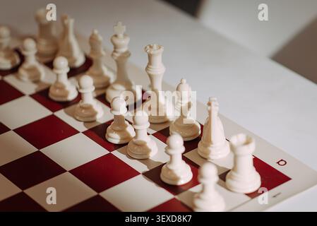 White chess pieces arranged on chessboard before strategic game Stock Photo