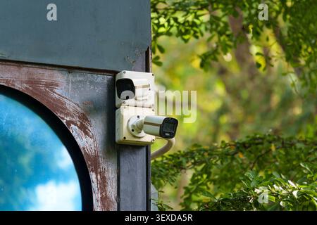 Two outdoor CCTV security surveillance cameras mounted on building corner in the garden Stock Photo