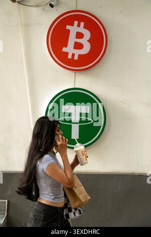 A woman with long dark hair is holding a cardboard box while standing in front of a wall featuring two circular signs. Stock Photo