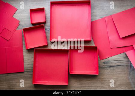 Lids from a red collapsible gift box gathered on a wooden table. Preparing a surprise. Stock Photo