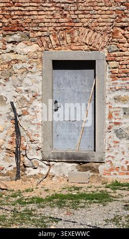 A vertical close-up shot displays a closed grey iron door framed by massive cut stones under a historic arched brick header Stock Photo