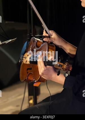 Close-up of a musician's hands with a viola and its bow. The fingers press the strings with precision and care. The bow holds tension, ready for the n Stock Photo
