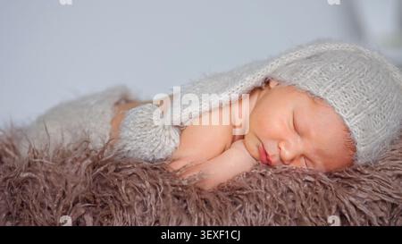 Newborn baby sleeping peacefully on soft brown fur blanket Stock Photo