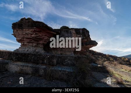 Layered rock outcrop with geological erosion against a blue sky Stock Photo