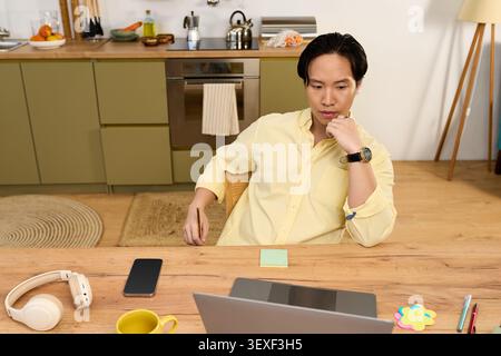 Relaxing in his cozy apartment, a young man contemplates his next move with focus Stock Photo