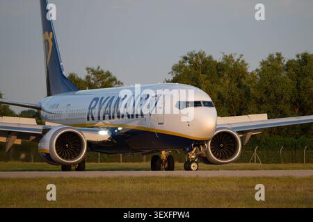 Ryanair Boeing 737 MAX 8-200 passenger airplane (EI-IKM) taxiing on the airfield at Bournemouth Airport during golden hour, UK. Stock Photo