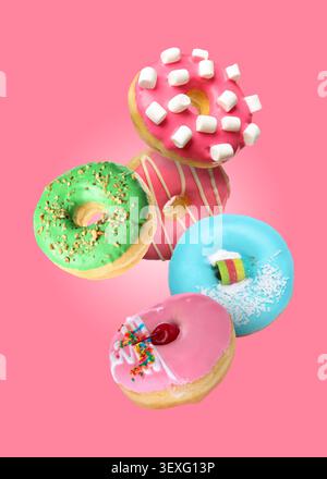 Yummy donuts covered with icing falling on pink background Stock Photo