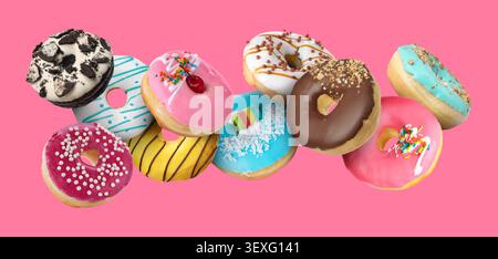 Sweet donuts covered with icing falling on pink background Stock Photo
