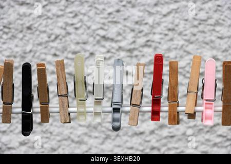 Coloured clothes pegs in a row on white background Stock Photo